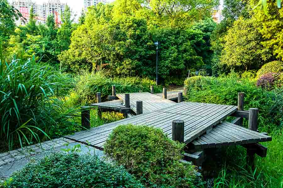 A landscaped park with lush green trees and wooden pathways and bridges